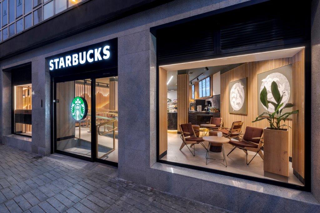 Light wood Akupanel acoustic slat wall panels inside Starbucks storefront with seating area.